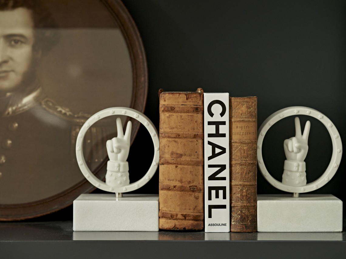 A curated arrangement of art objects and books, illustrating how contrasting pieces can be brought together to create a sense of eclectic elegance.
