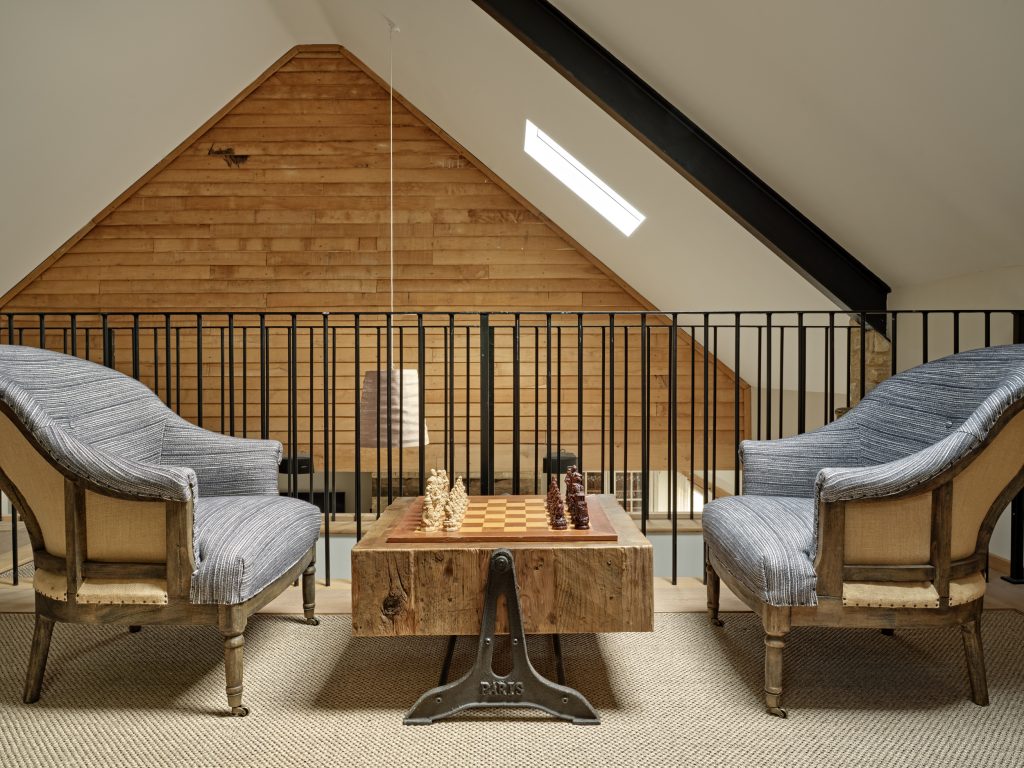 A calm upper-level sitting area where layout and circulation create a natural flow between spaces within a Cotswold family home.