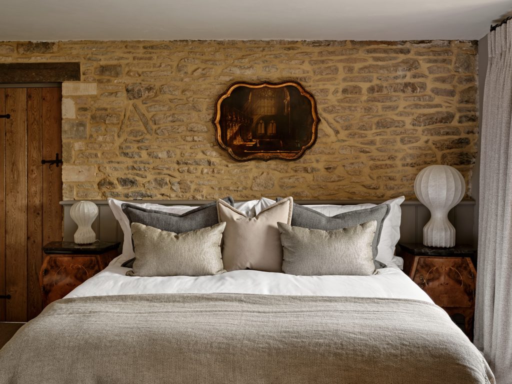 A layered bedroom interior with a mix of furniture and textiles, illustrating how pieces gathered over time create a calm, collected and characterful space.