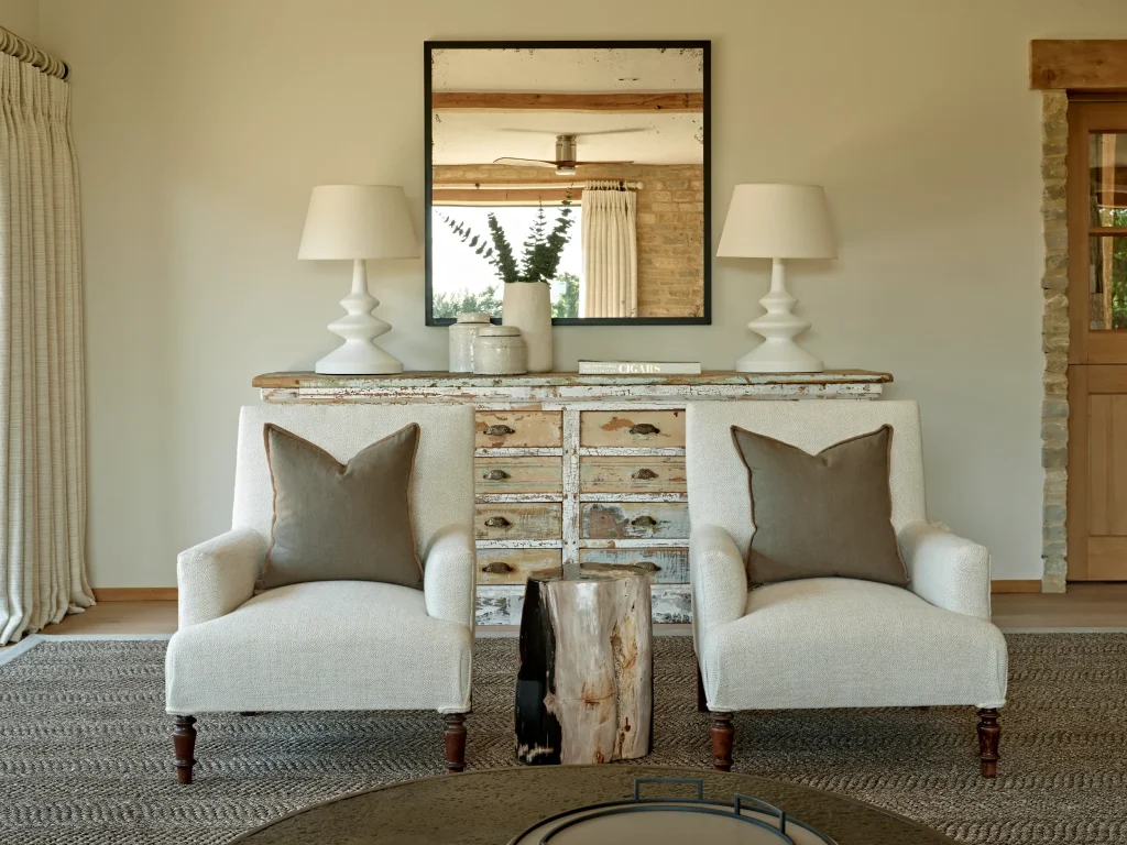 Symmetrical living room layout with armchairs, console table and mirror in a Cotswolds home